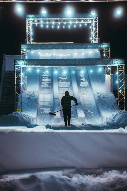 a man stands in front of a ski ramp at night