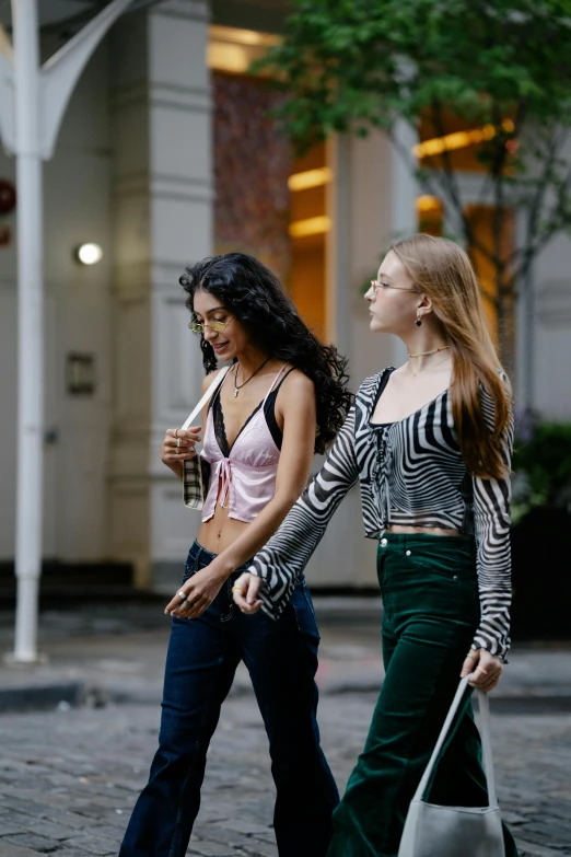 two young women walk down a street in front of a building