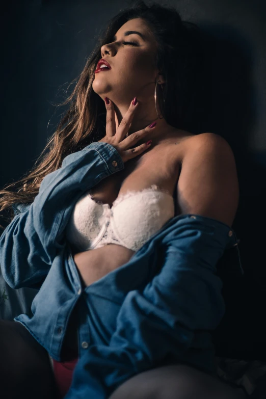 a beautiful woman sitting on top of a bed with her hands to her chest