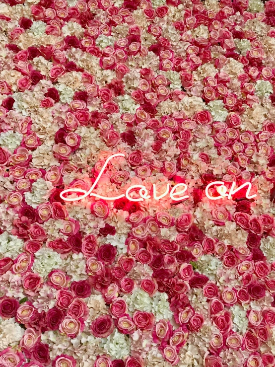 a bed covered in pink flowers and with a white lettering on top