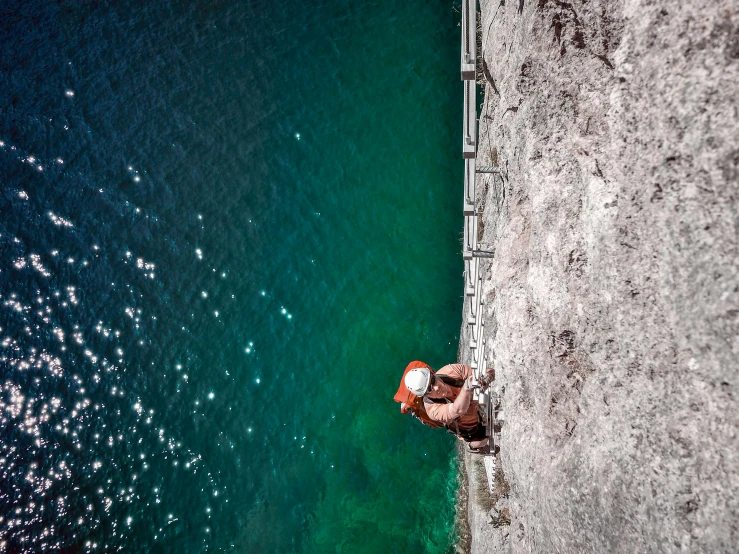 a man sitting on a ledge near the ocean