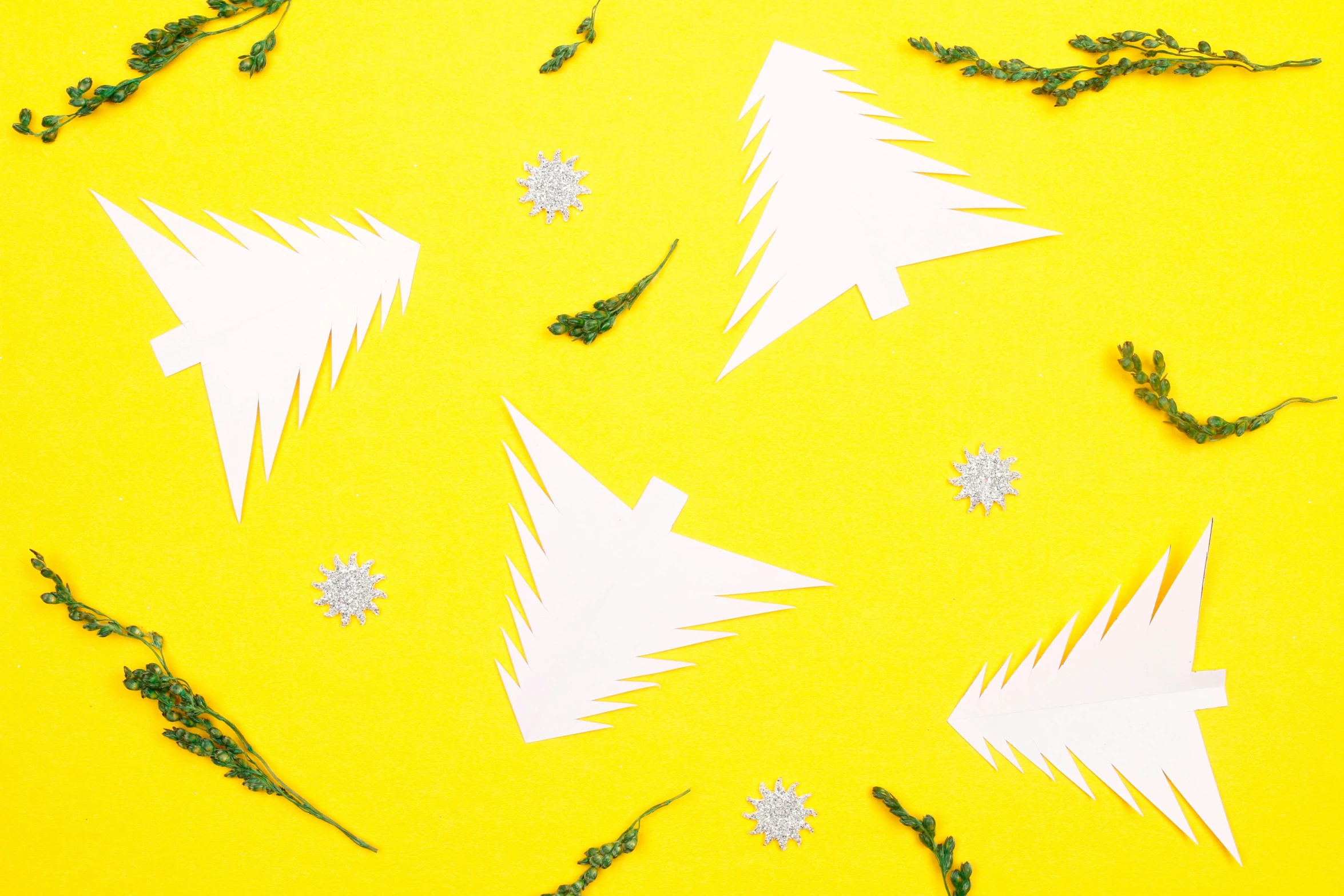 some cut out white christmas trees on a yellow surface