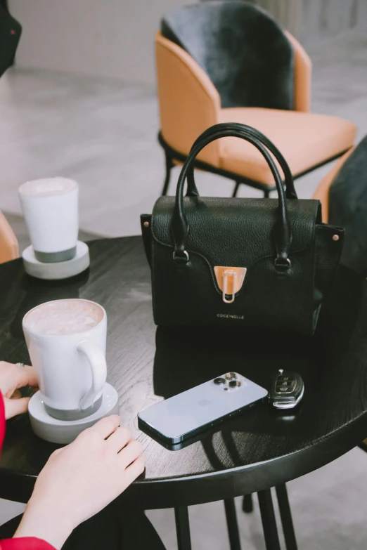 a woman sitting at a table in front of a purse and a cell phone