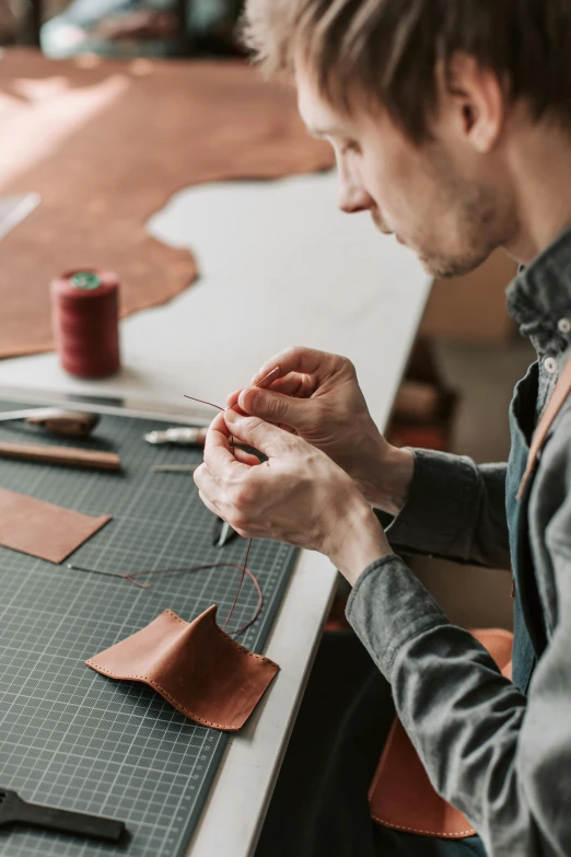 a man is sitting at a table working on leather