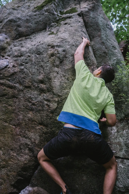 a young man on some rocks with his hand up