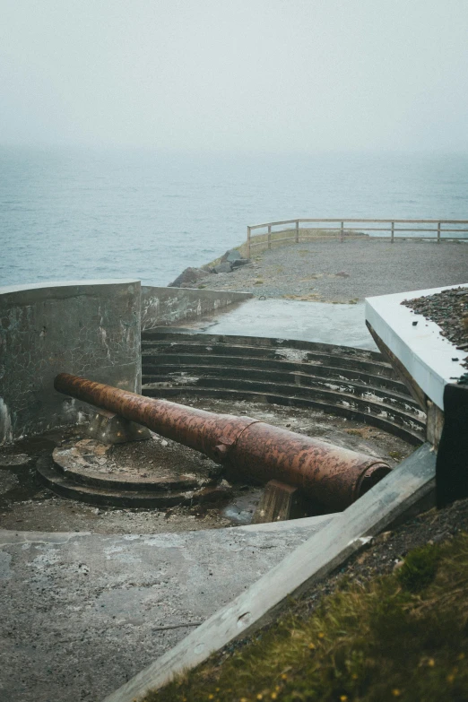 an old pipe laying on the ground near the ocean