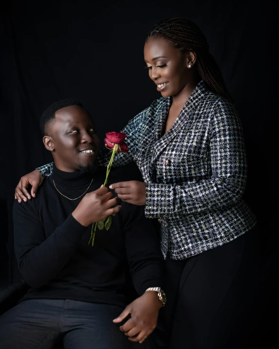 a woman holding onto a man with a rose in his lap