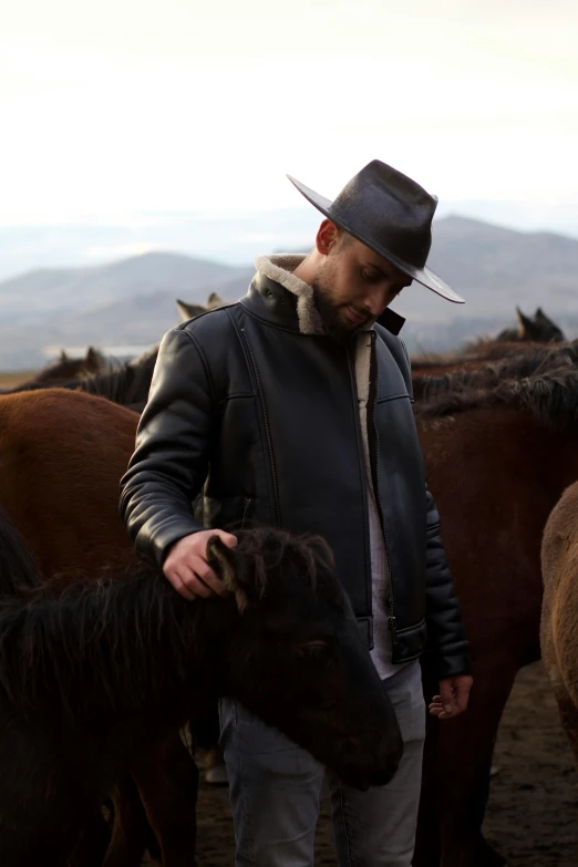 a man petting a pony wearing a hat