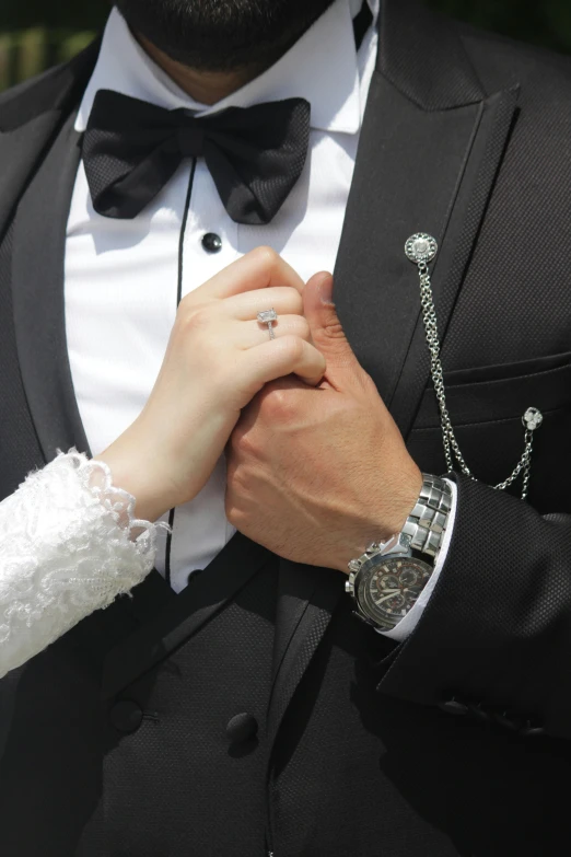 a man wearing a suit and diamond ring clasps the mans wrist