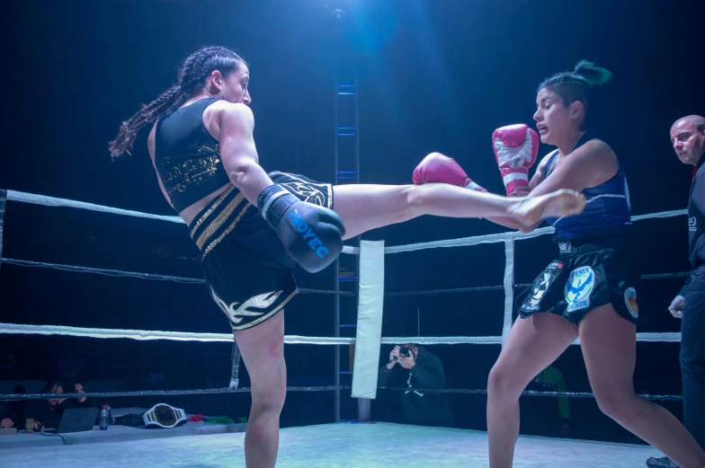 women on boxing rings with one woman kicking the kick