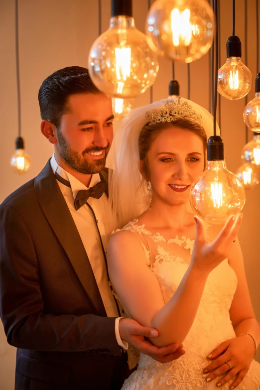 the bride and groom stand next to each other with lights on them