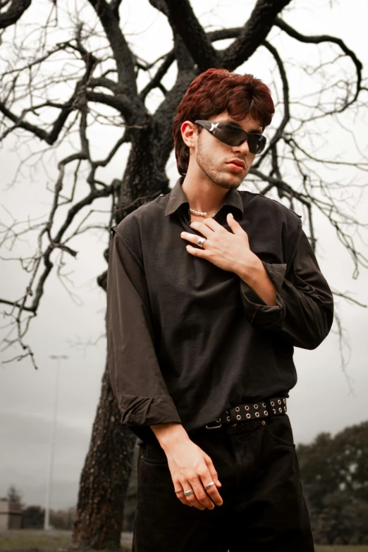 a man in sunglasses and black shirt next to a tree