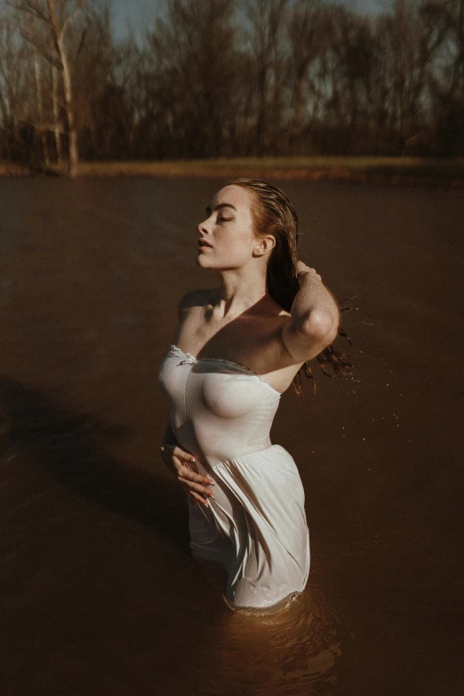 a woman standing in water while holding her hand behind her ear
