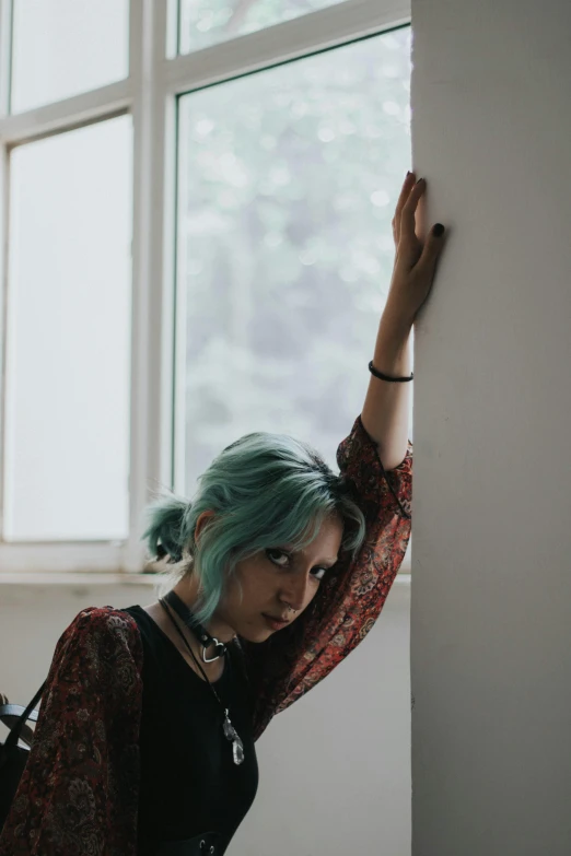 woman with blue hair leaning up against a wall