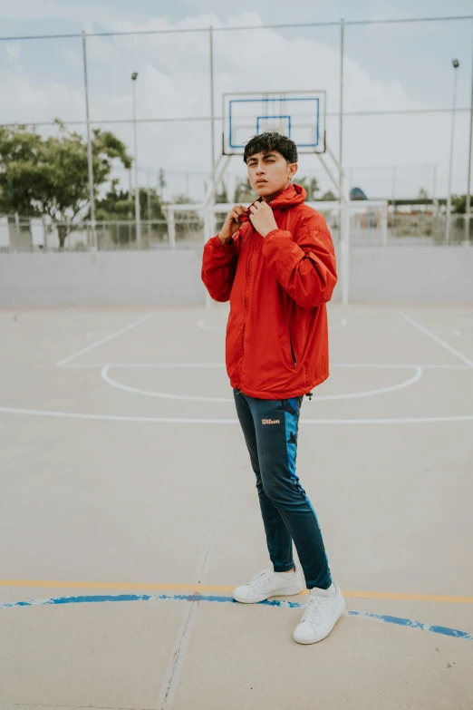 the man is posing in front of the basketball court