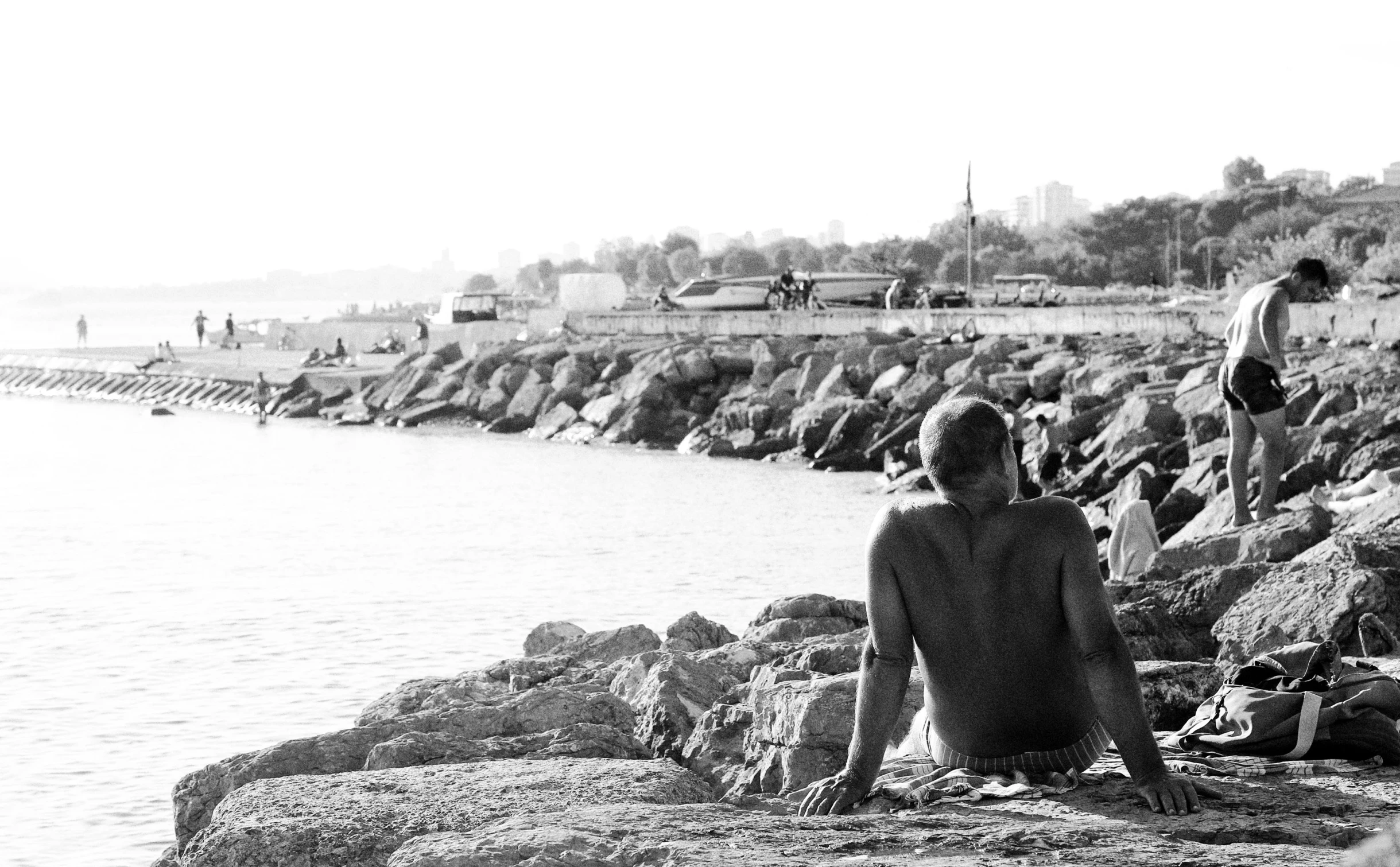 a man sitting on rocks watching the water