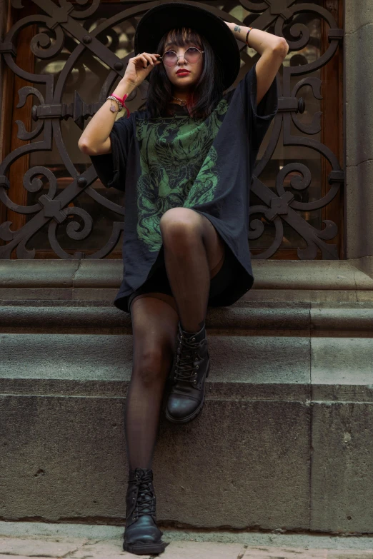 a woman sitting on steps with a black hat and green shirt