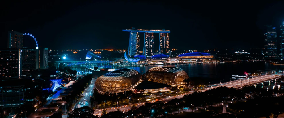 city buildings with tall buildings, a body of water and lights at night