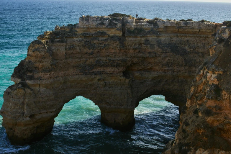 an arch shaped rock formation next to the ocean