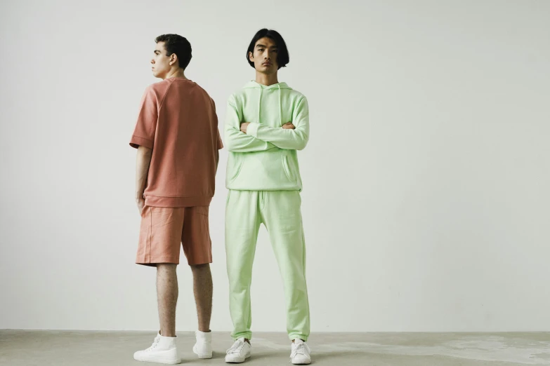 two men standing next to each other while wearing paste colored clothing