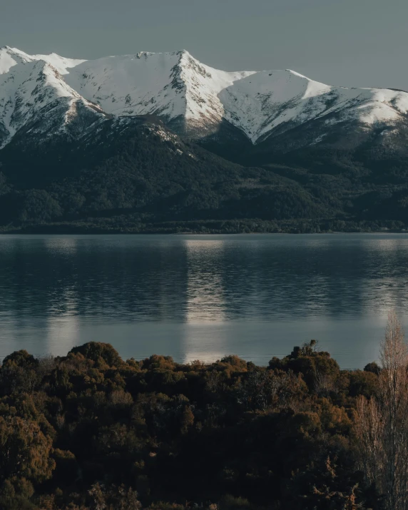 mountains with snow around them are reflecting on the water