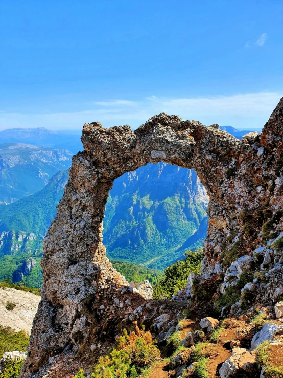 an arch in a rock formation near the mountains