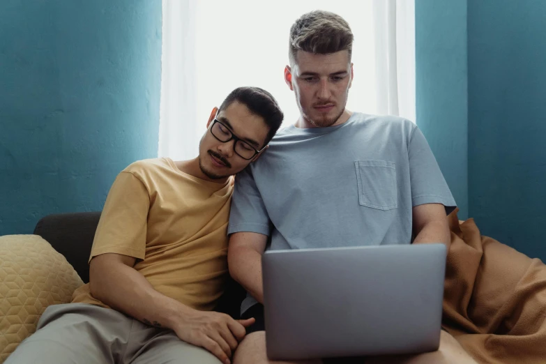 a man sitting next to another mans with a laptop computer