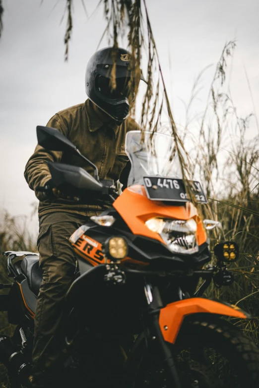 a man in a helmet and orange jacket is riding an orange motorcycle