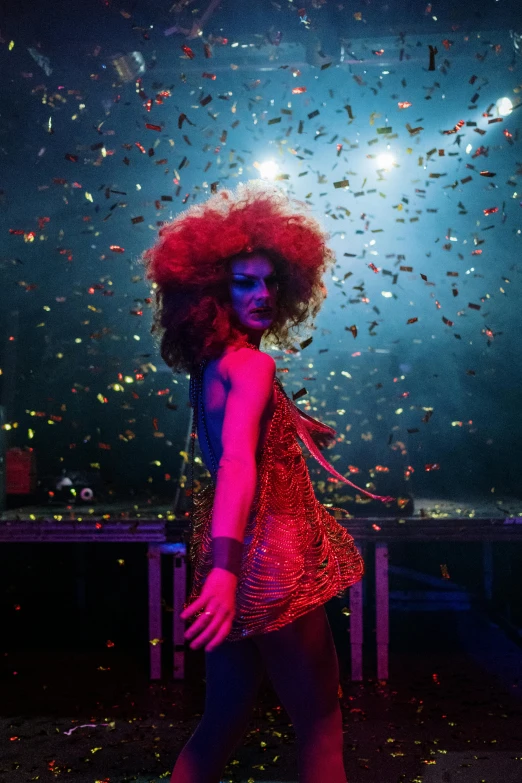 a woman with red hair walking through a tunnel of confetti