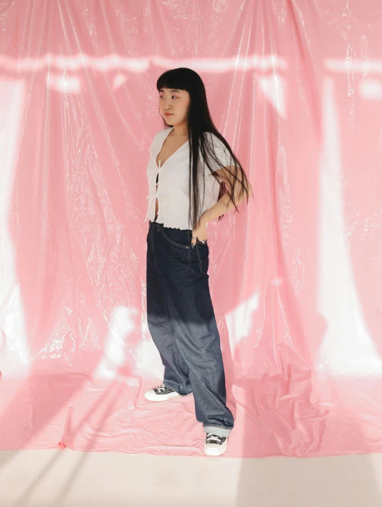 a woman wearing blue pants in front of pink backdrop