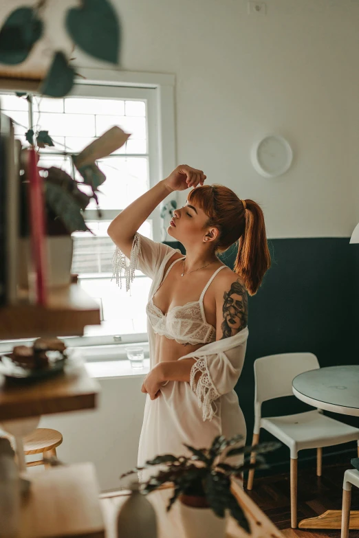 a woman wearing a  is standing in the kitchen looking at soing on the counter