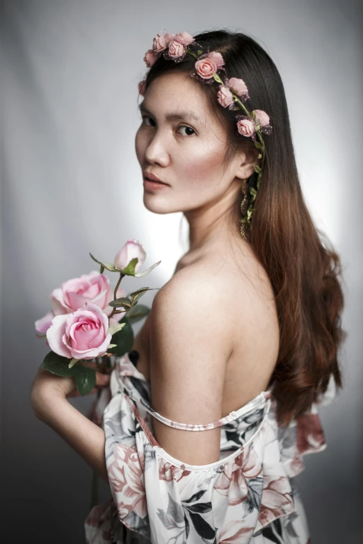 a young lady with flower crown on her head holding a pink rose