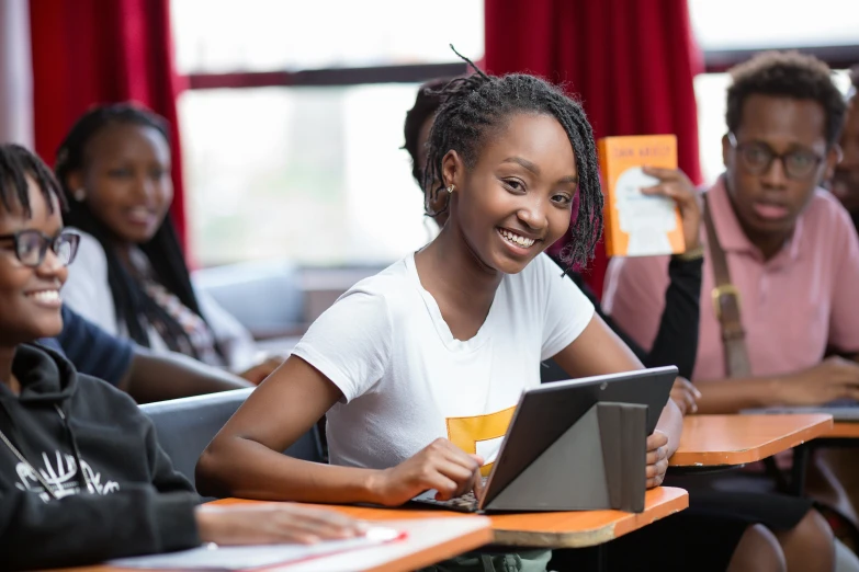 a woman sitting at a table holding a book and a laptop