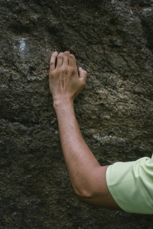 a person holding a hand against the side of a rock