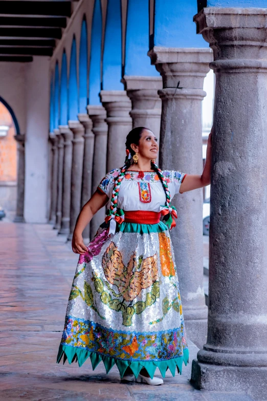 a woman standing under a pillar with a very colorful dress