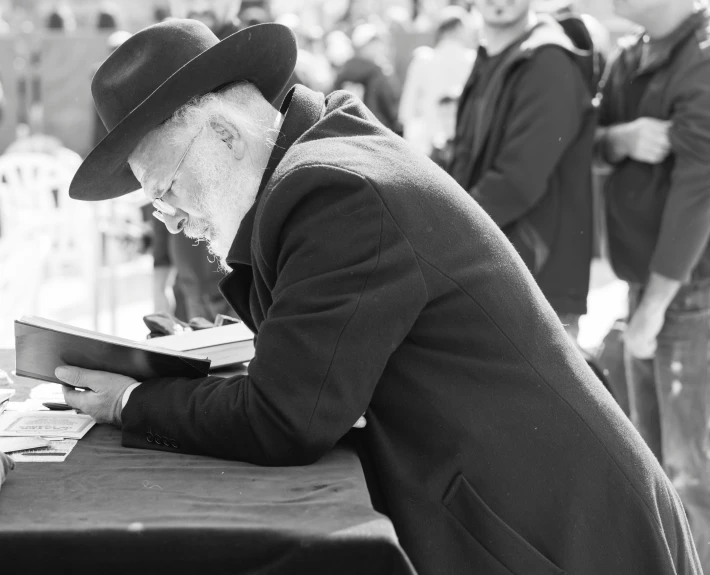 man in old fashioned suit looking at the viewer through an open book