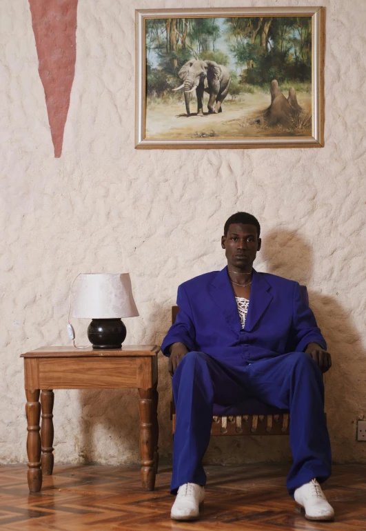 an african american man in blue sitting on a wooden chair