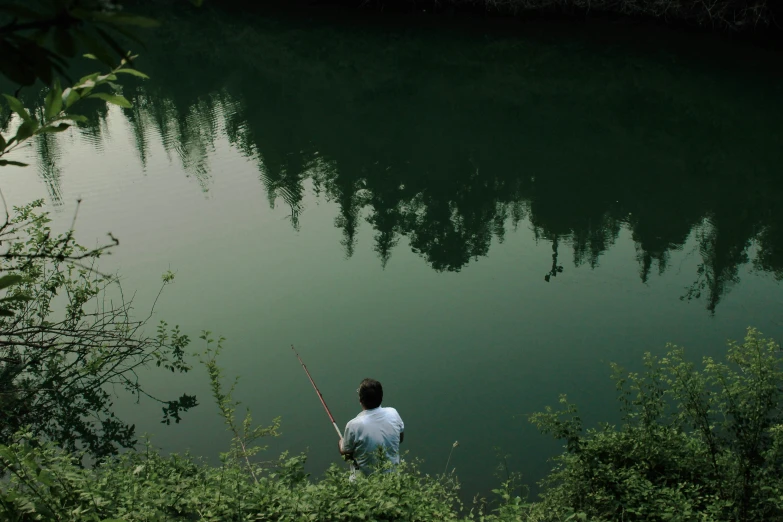 there is a man sitting on a bank fishing