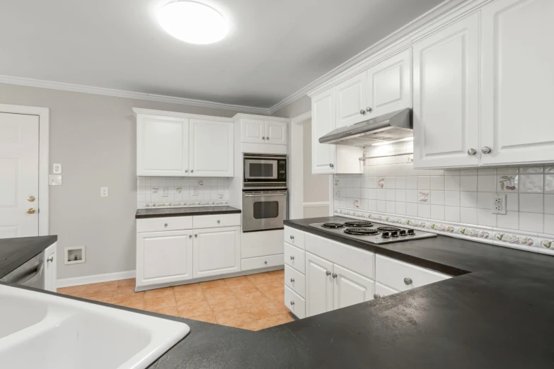 a view of a kitchen with black countertops and white cabinets