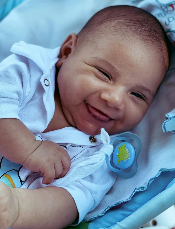 a small baby lying on a blue blanket smiling