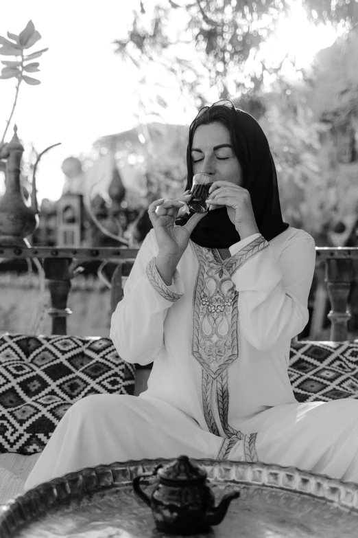 a woman sitting in the shade, holding a camera to her face