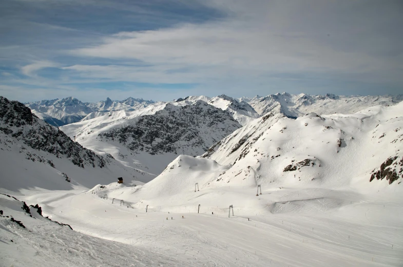 the view of a mountain range with several skiers skiing down it