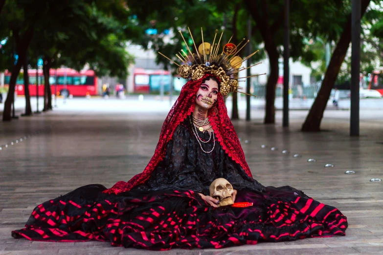 a woman dressed in elaborate clothing with red hair and a skull