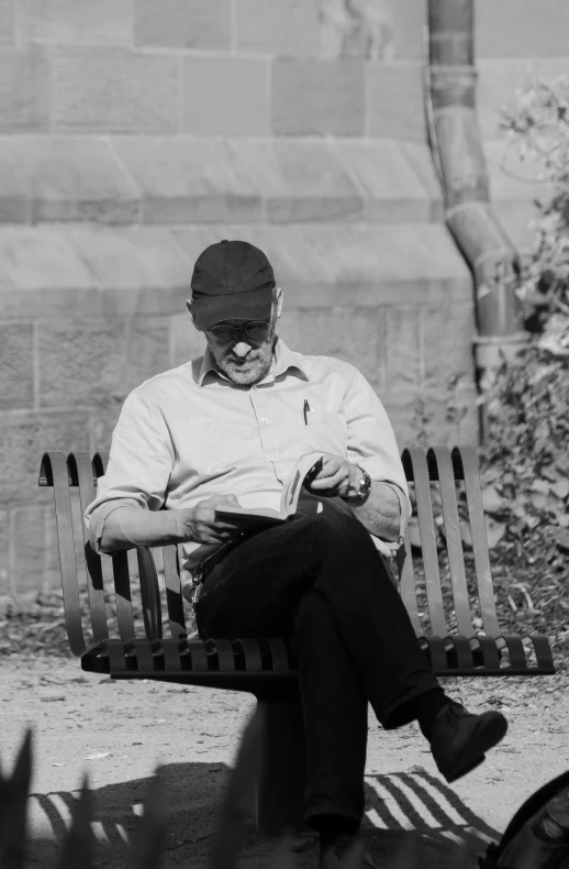 man on bench, reading in outdoor setting