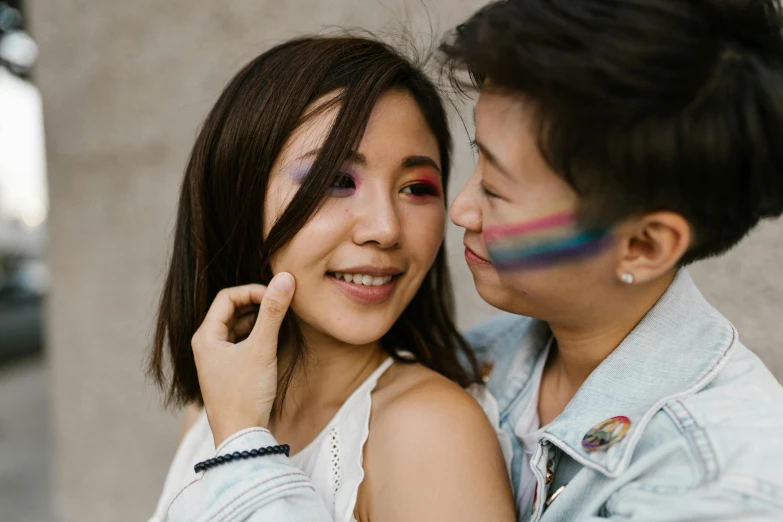 a woman smiles as another holds her face