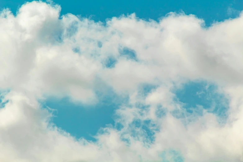 a large white and blue plane flying under a cloudy sky