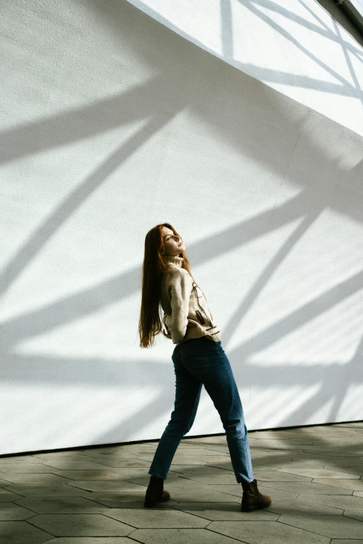 a woman standing in front of a white wall with her hair blowing back