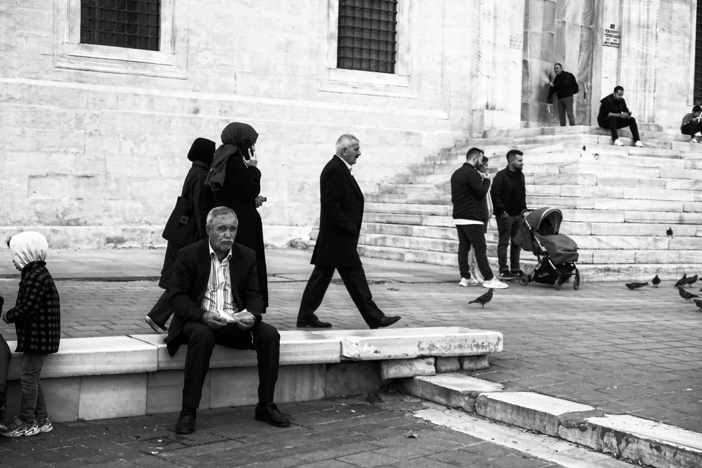 people walking around in front of steps that lead to a building