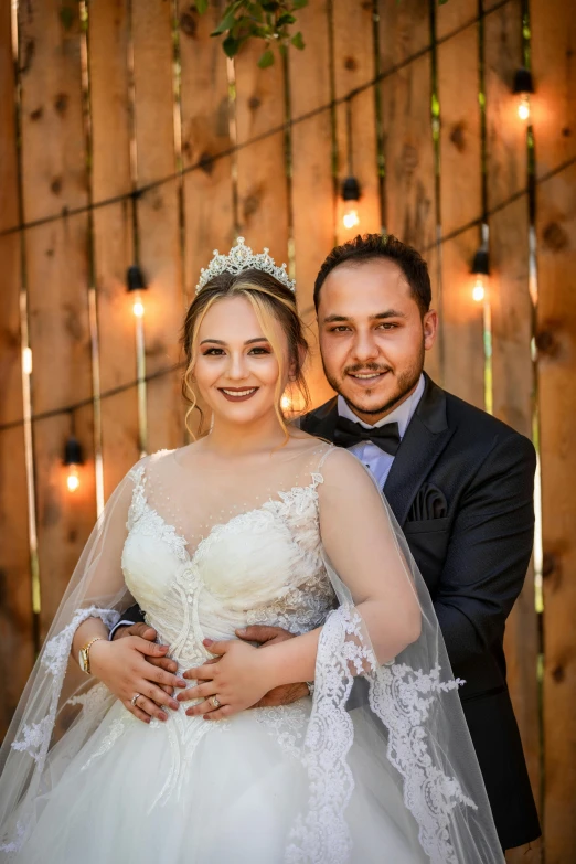 a bride and groom pose in front of a wood - paneled wall