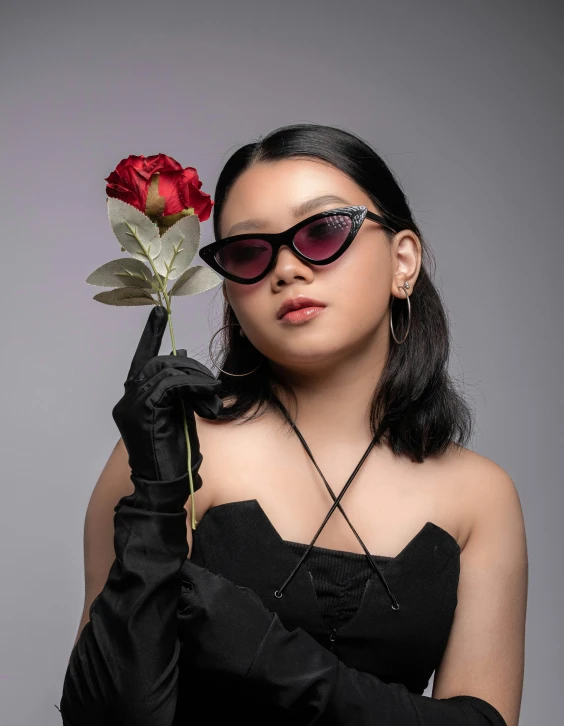 woman in black dress holding a flower on gray